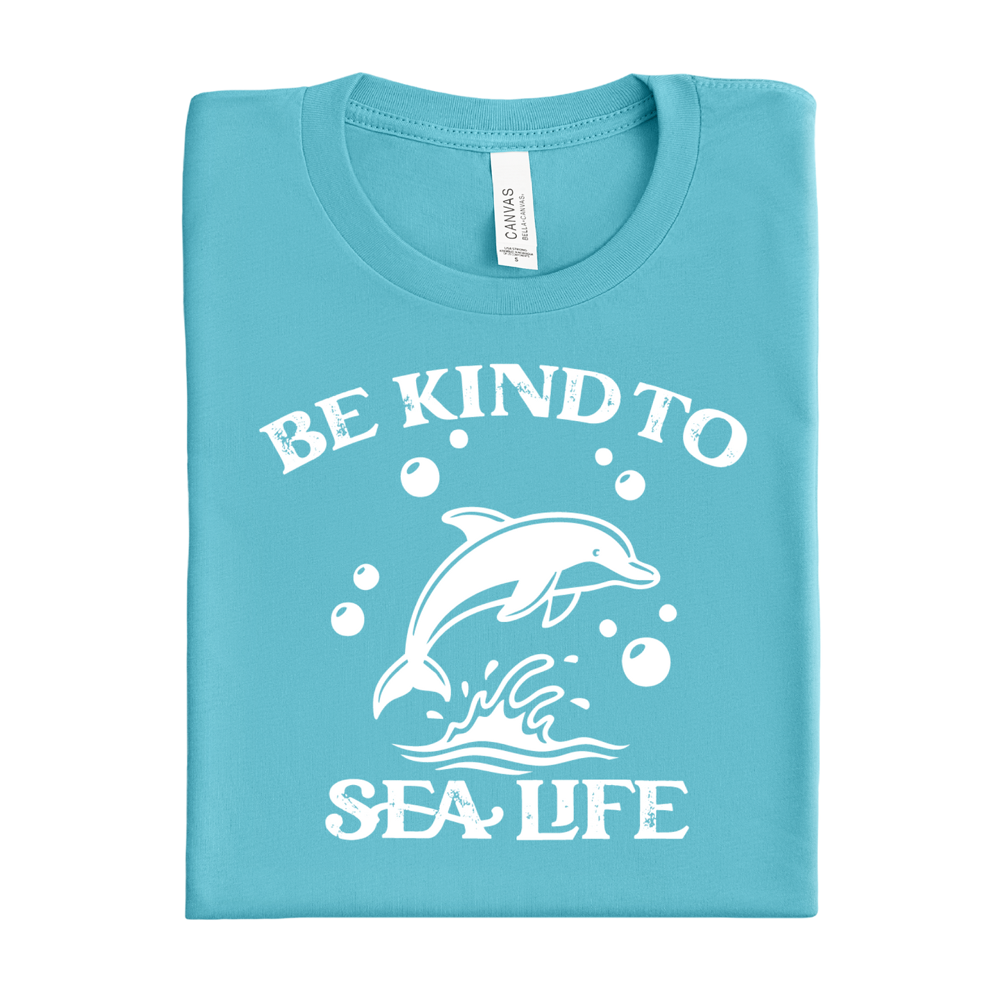 Folded turquoise t-shirt with white dolphin graphic and text 'Be Kind to Sea Life' on a white background