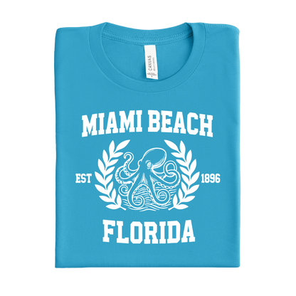Folded aqua blue t-shirt with 'Miami Beach Florida' text and octopus design on a white background