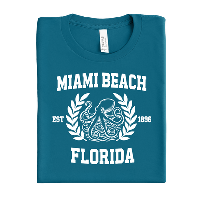 Folded deep teal t-shirt with 'Miami Beach, Florida' text and octopus design on a white background