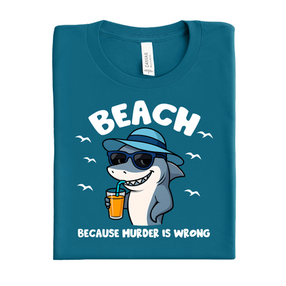 Folded deep teal t-shirt with a shark graphic and text on a white background