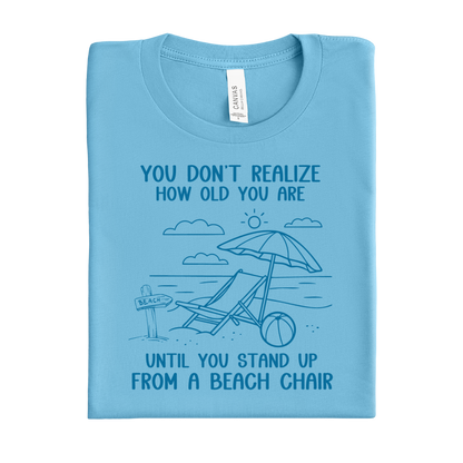 Folded ocean blue t-shirt with beach graphic and text on a white background