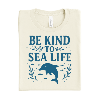 Folded t-shirt with 'Be Kind to Sea Life' text and dolphin graphic on a white background