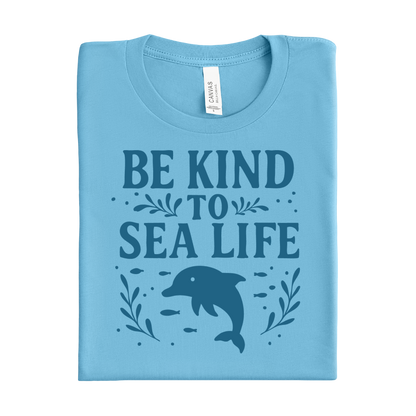 Folded ocean blue t-shirt with 'Be Kind to Sea Life' text and dolphin graphic on a white background