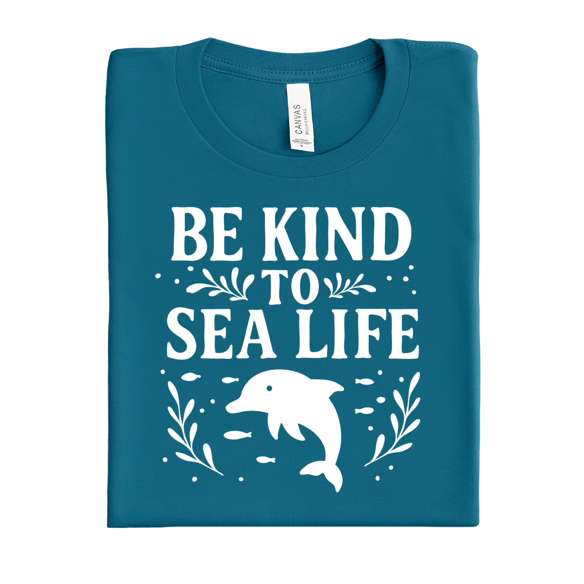 Folded deep teal t-shirt with 'Be Kind to Sea Life' text and dolphin graphic on a white background