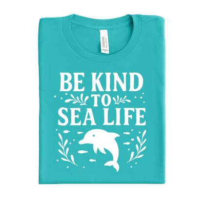 Folded teal t-shirt with 'Be Kind to Sea Life' text and dolphin graphic on a white background