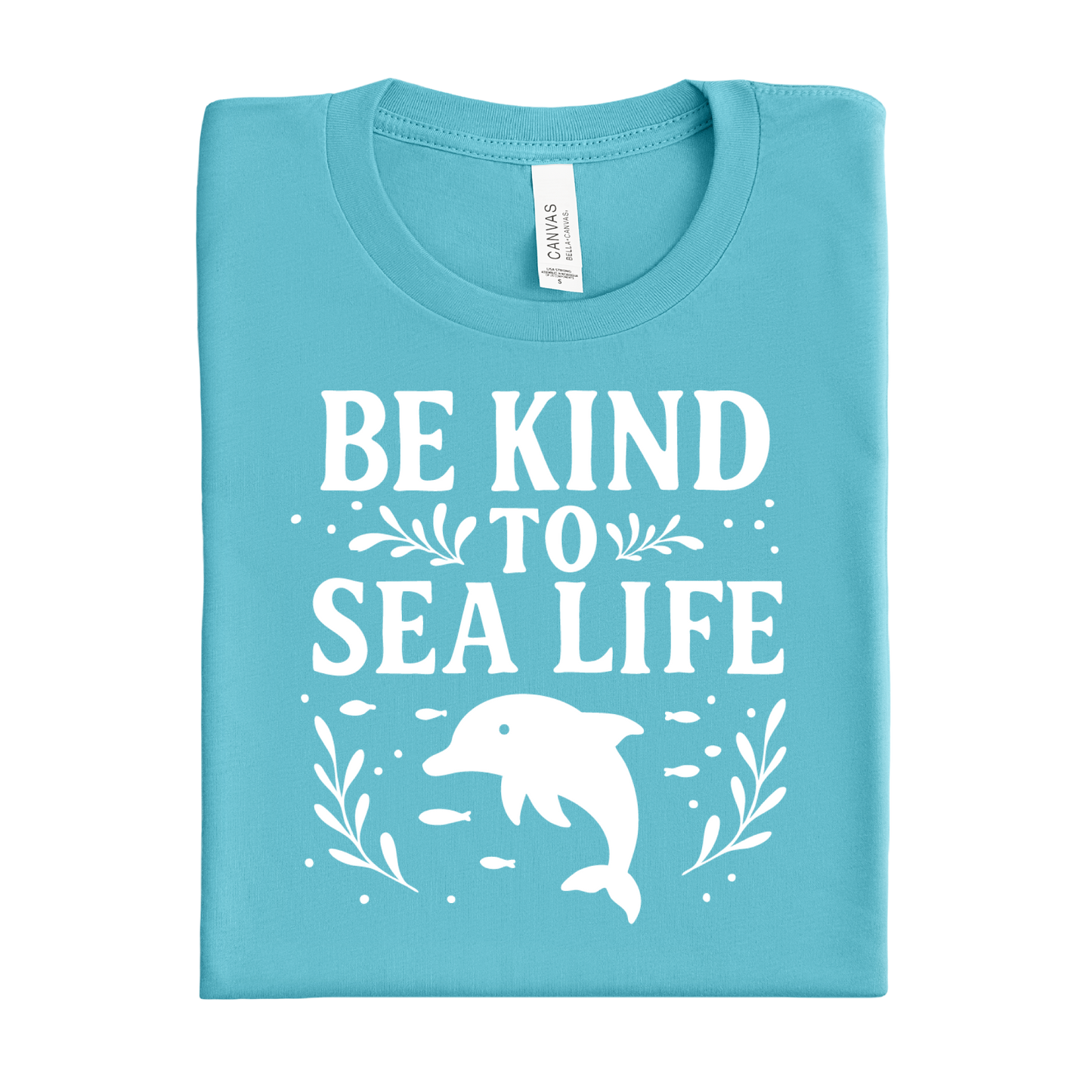 Folded turquoise t-shirt with 'Be Kind to Sea Life' text and dolphin graphic on a white background