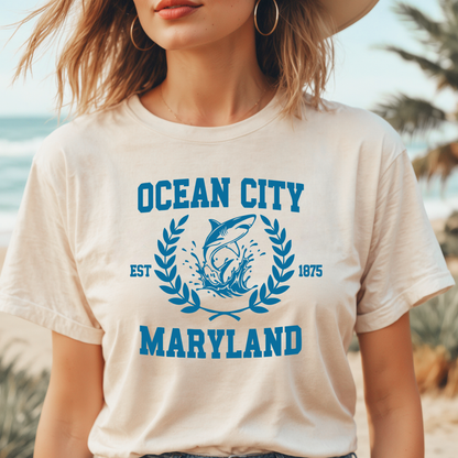 Person wearing a 'Ocean City, Maryland' t-shirt with a shark graphic on a beach.
