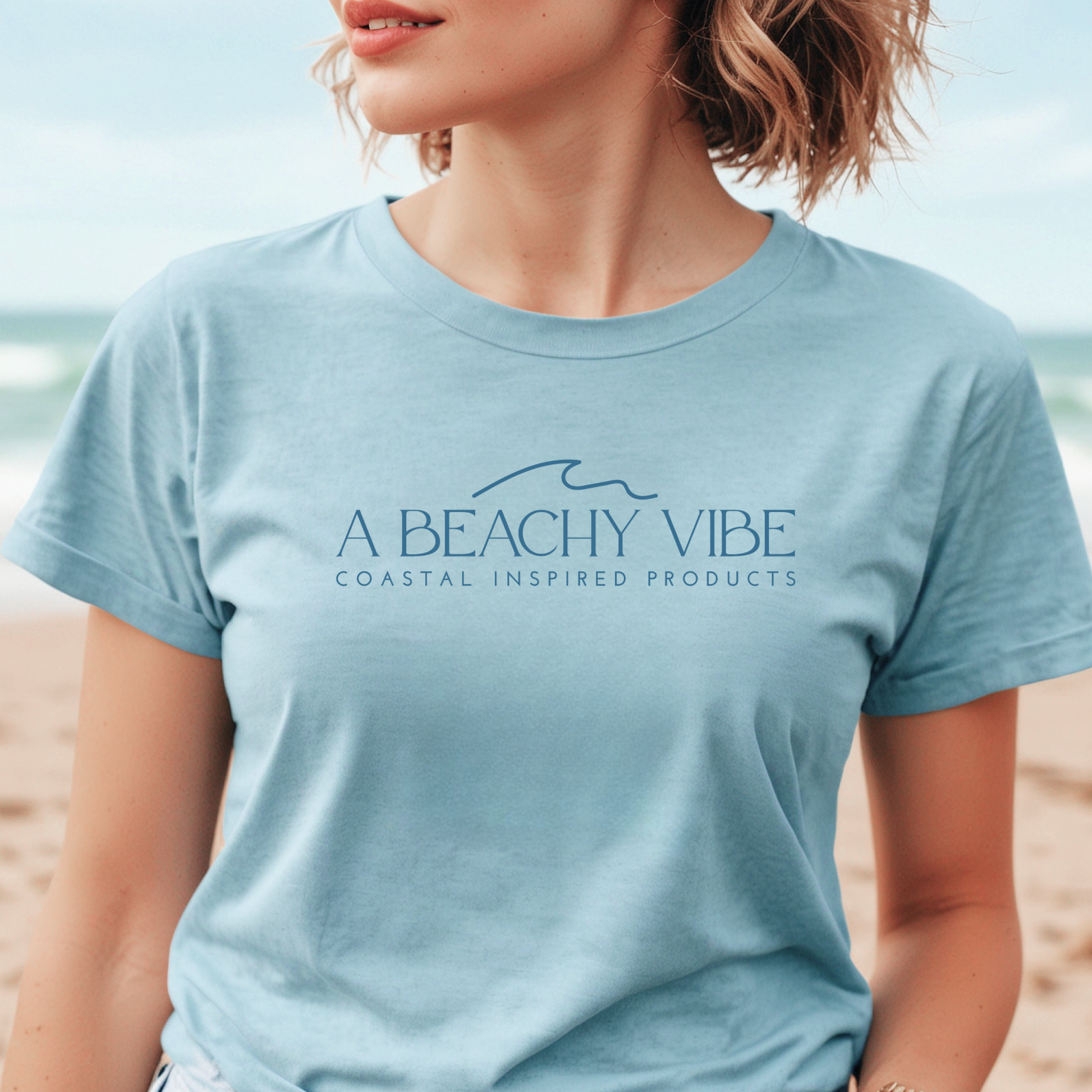 Bella Canvas 3001 "A Beachy Vibe" t shirt with a simple wave graphic with text and one color graphic. Picture of a girl on the beach in a t shirt.