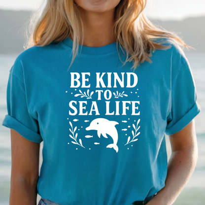 Person wearing a blue t-shirt with 'Be Kind to Sea Life' and a dolphin graphic.