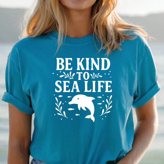 Person wearing a blue t-shirt with 'Be Kind to Sea Life' and a dolphin graphic.