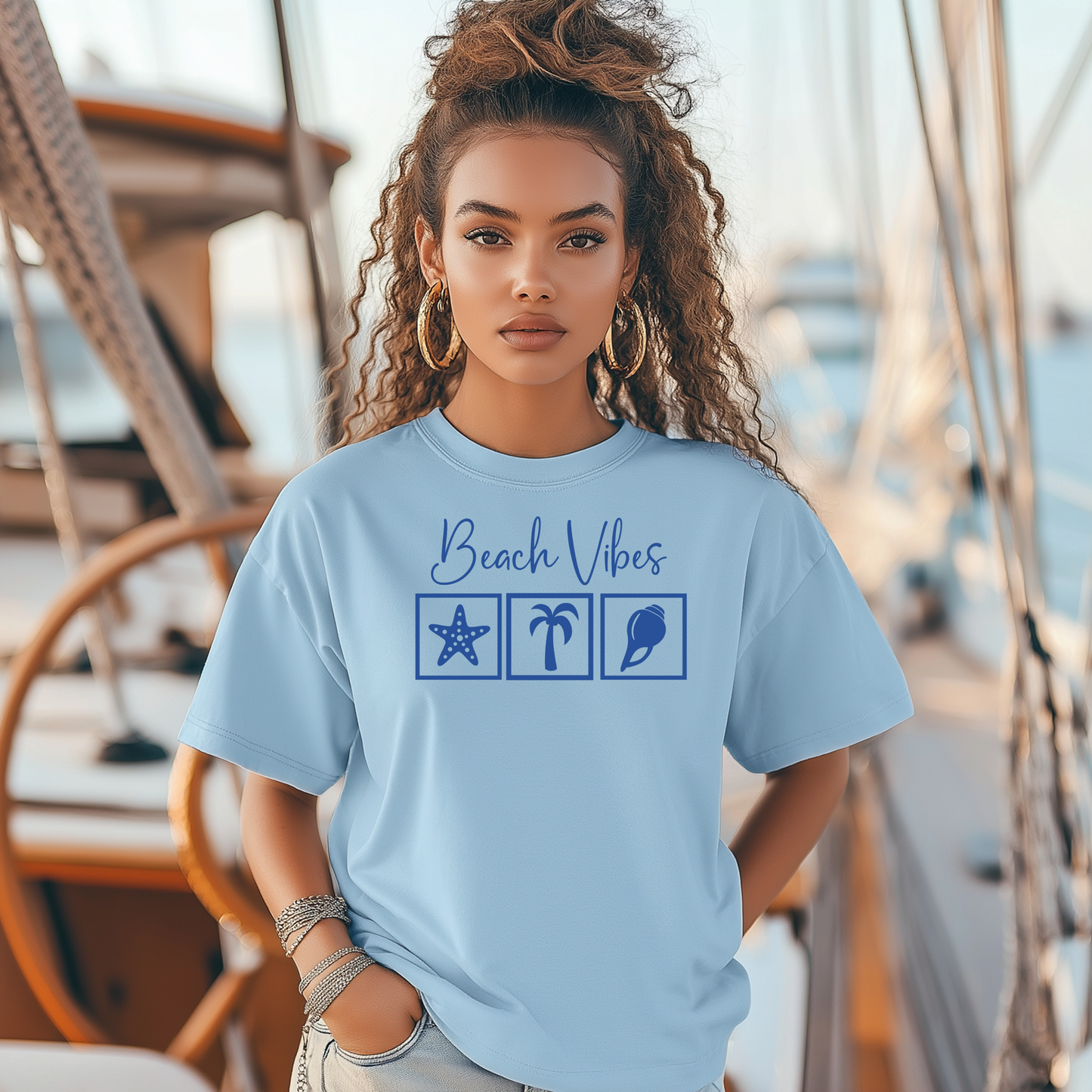 Bella and Canvas 3001 "Beach Vibes" t shirt with a starfish, palm tree, and a seashell graphics in monochrome color. Picture of a girl standing on a boat  wearing a t shirt.