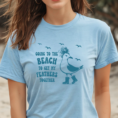 Person wearing a light blue t-shirt with a seagull graphic and text on a beach.