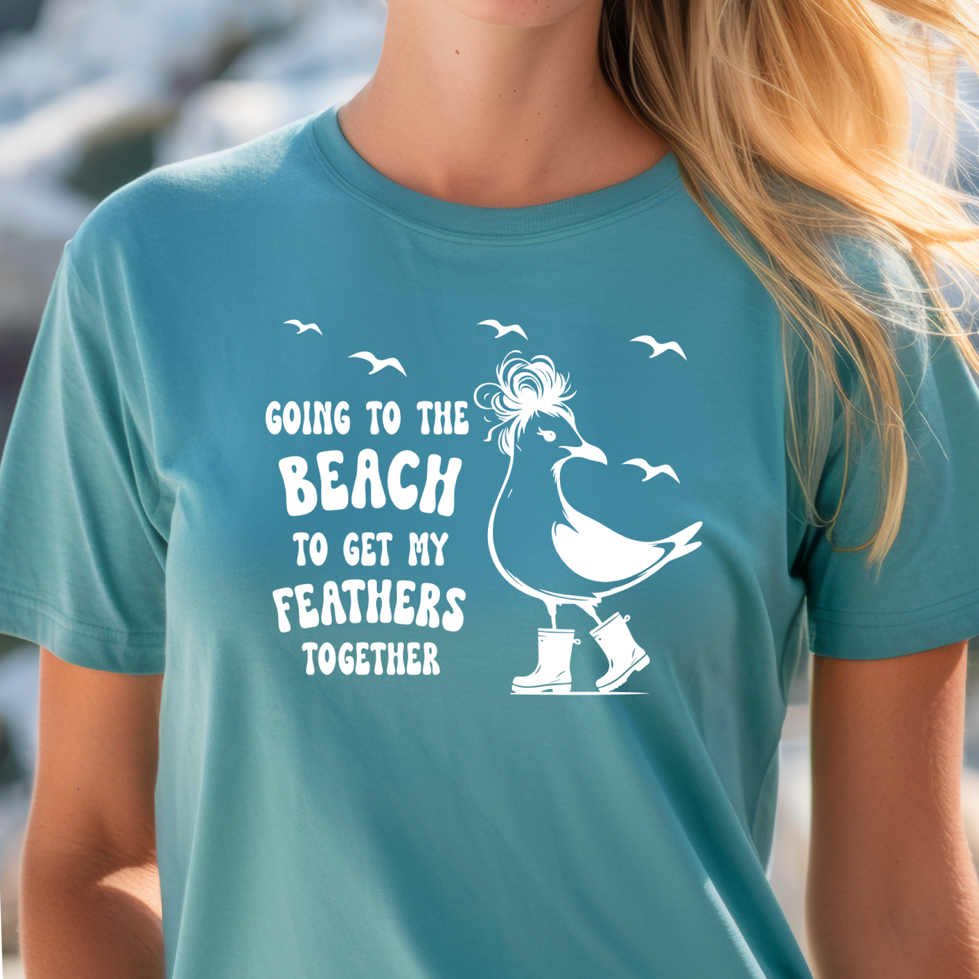 Person wearing a Turquoise t-shirt with a graphic and text about going to the beach.