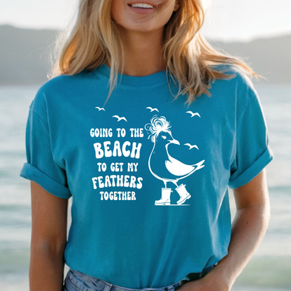 Person wearing a aqua blue t-shirt with a beach-themed design and text.