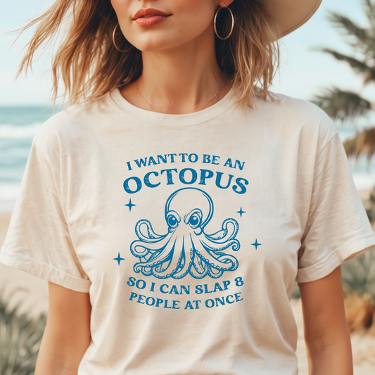 Person wearing a t-shirt with an octopus graphic and text by the beach