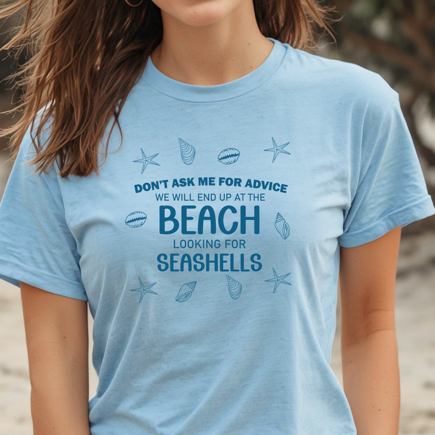 Person wearing a light blue t-shirt with beach-themed text and graphics.