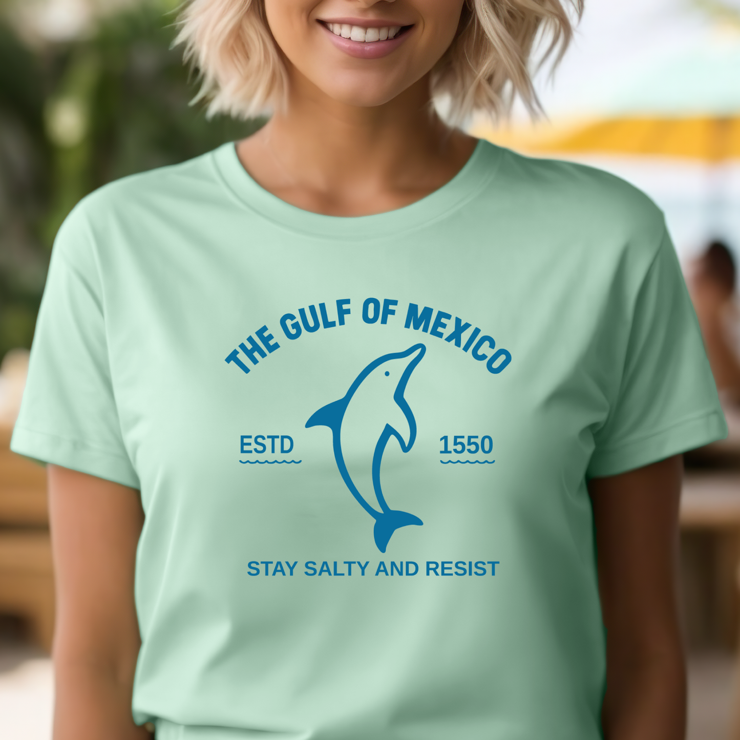 Person wearing a light green t-shirt with a dolphin graphic and text about the Gulf of Mexico.