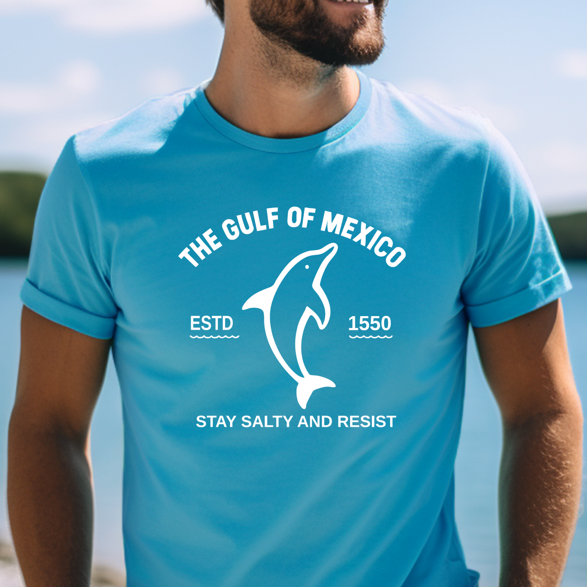 Person wearing a aqua  blue t-shirt with a dolphin graphic and text about the Gulf of Mexico.