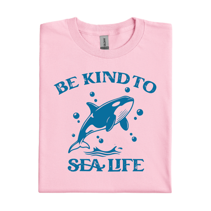 Pink t-shirt with blue orca and text 'Be Kind to Sea Life' on a white background