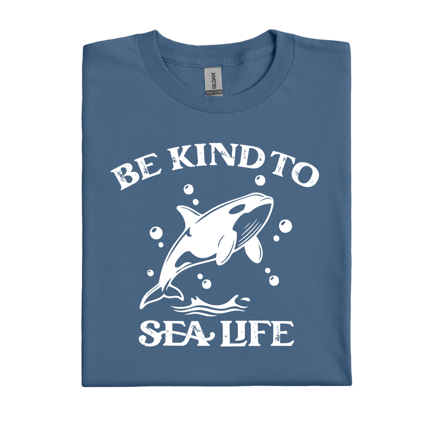 Folded indigo blue t-shirt with a white whale graphic and text 'Be Kind to Sea Life' on a white background
