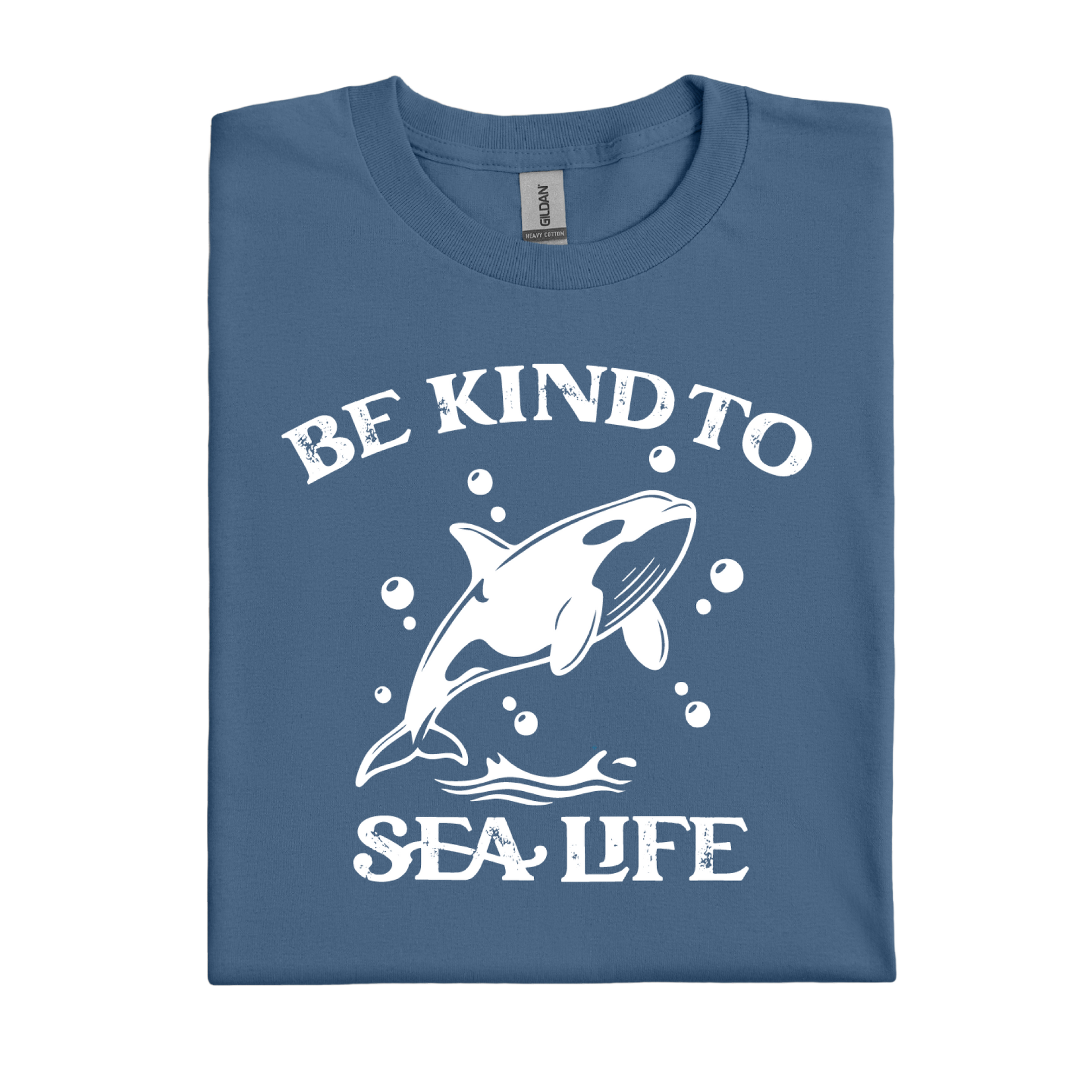 Folded indigo blue t-shirt with a white whale graphic and text 'Be Kind to Sea Life' on a white background
