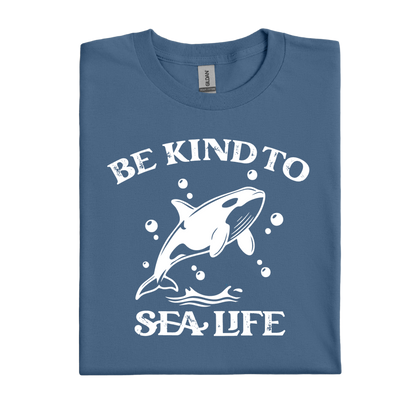 Folded indigo blue t-shirt with a white whale graphic and text 'Be Kind to Sea Life' on a white background