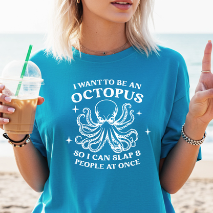 Person wearing a sapphire blue t-shirt with an octopus graphic and text on a beach.