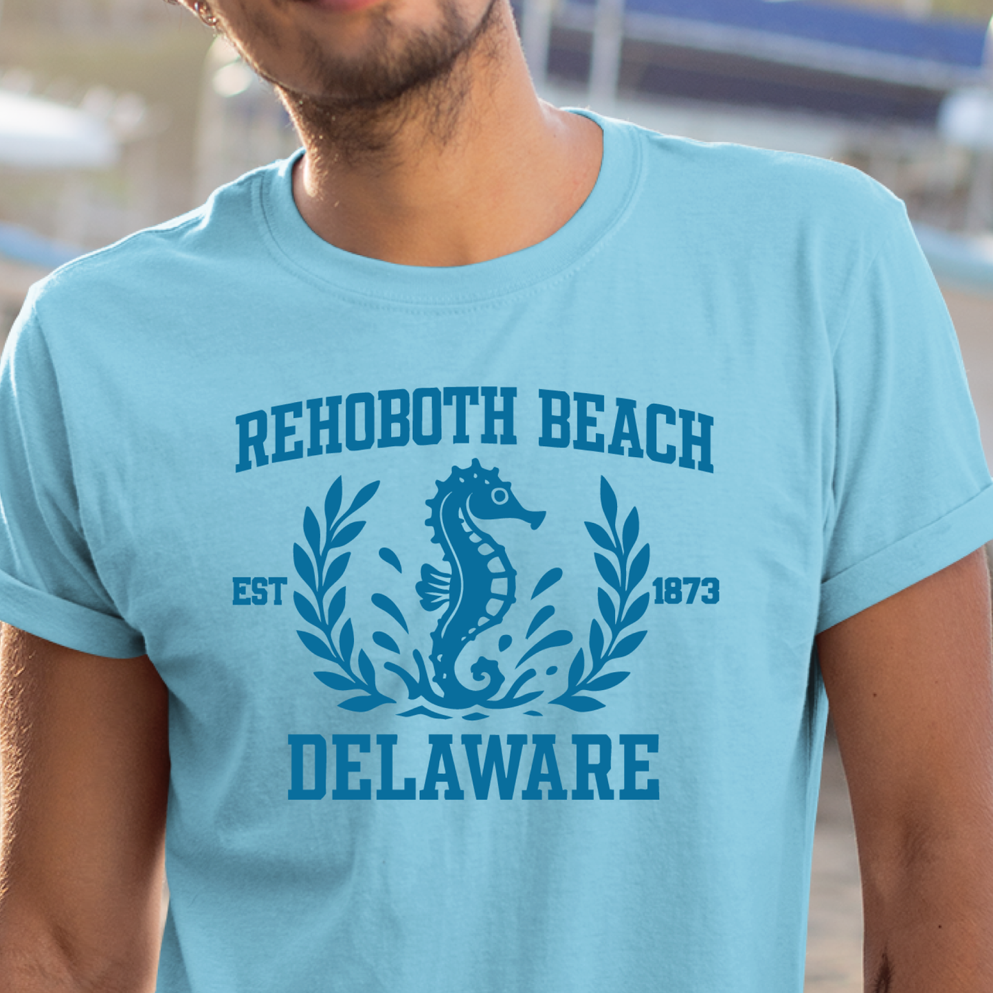 Person wearing a sky blue t-shirt with Rehoboth Beach, Delaware design.