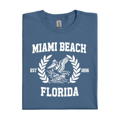 Folded indigo blue t-shirt with 'Miami Beach Florida' text and graphic on a white background