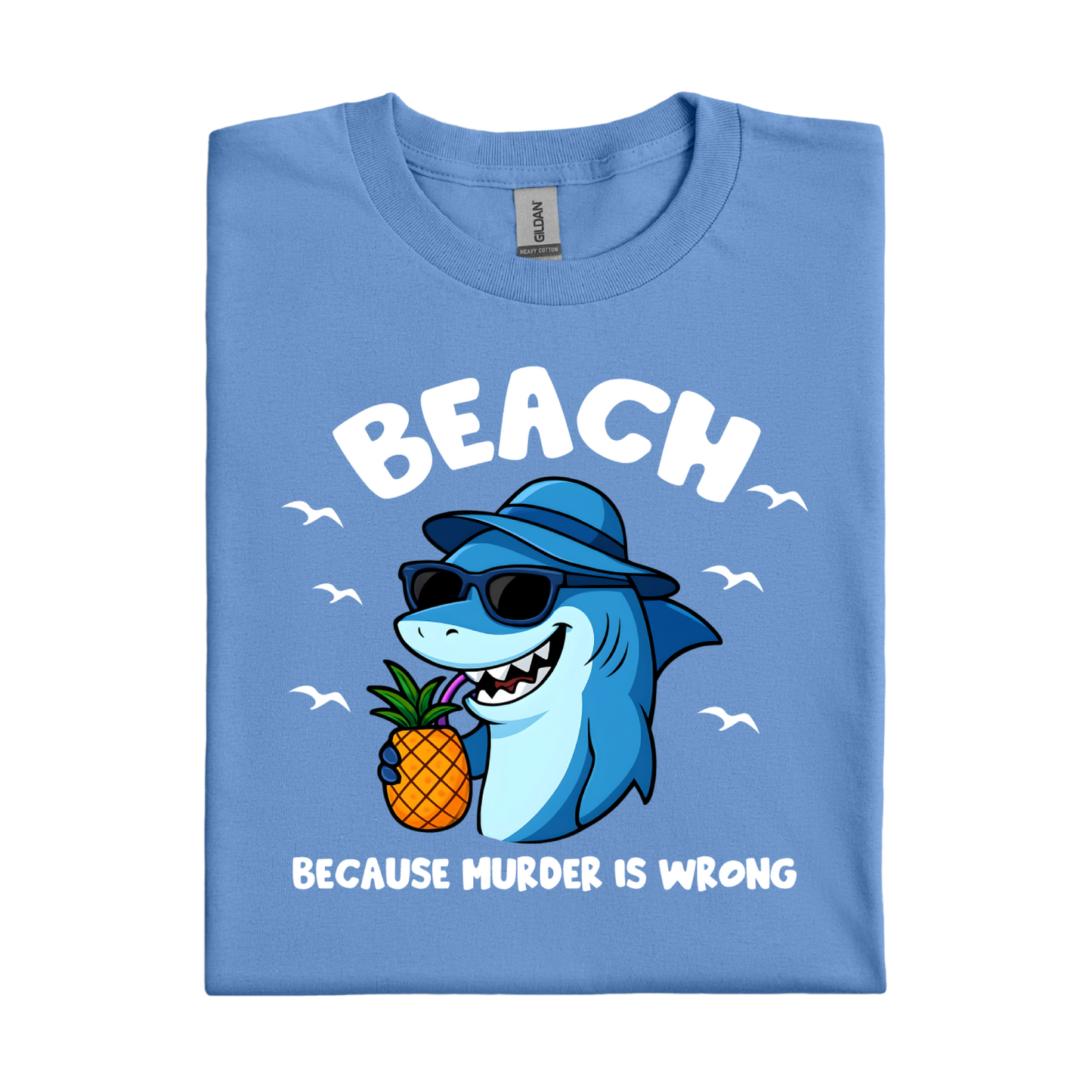 Folded Carolina blue t-shirt with a shark holding a pineapple and text on a white background