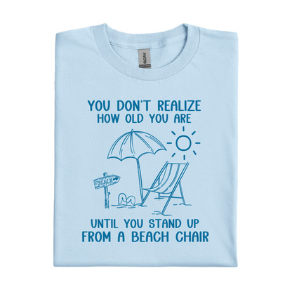 Light blue t-shirt with beach-themed design and text on a white background