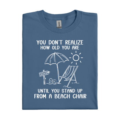 Folded indigo blue t-shirt with beach-themed graphic and text on a white background