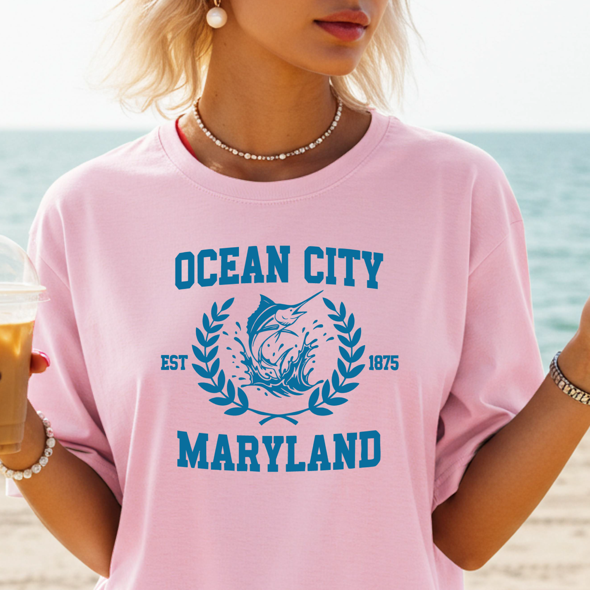 Person wearing a pink t-shirt with 'Ocean City, Maryland' design on a beach.