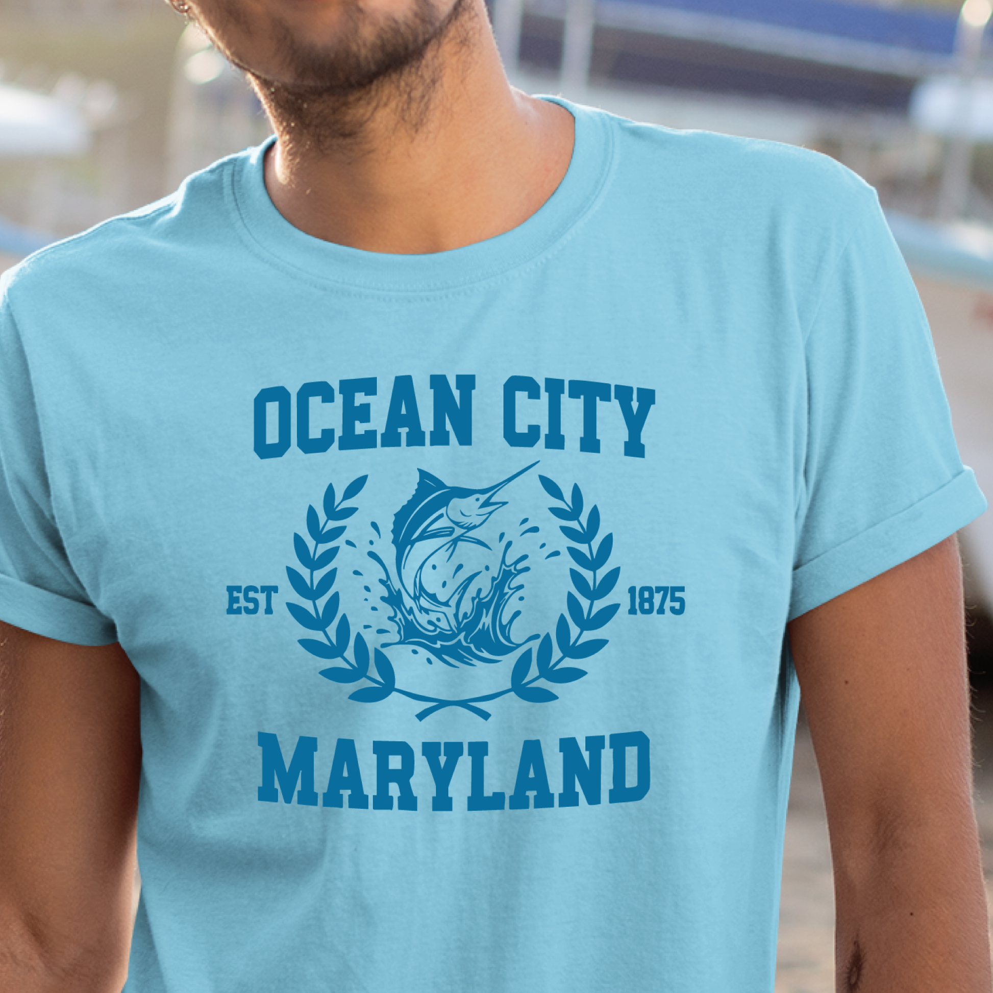 Person wearing a ocean blue t-shirt with 'Ocean City, Maryland' text and marlin graphic.