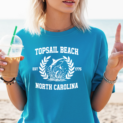 Person wearing a sapphire blue 'Topsail Beach, North Carolina' t-shirt with a shark graphic on a beach.