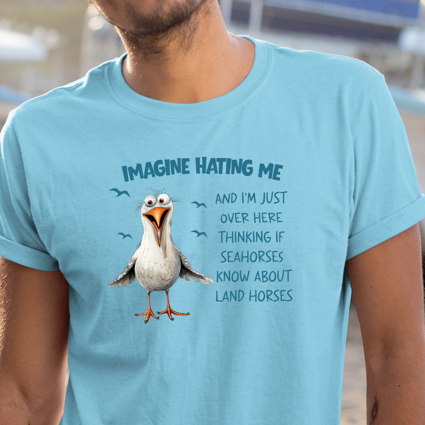 Person wearing a sky blue t-shirt with a cartoon seagull and humorous text.