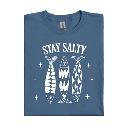 Folded indigo blue t-shirt with 'Stay Salty' text and fish graphics on a white background
