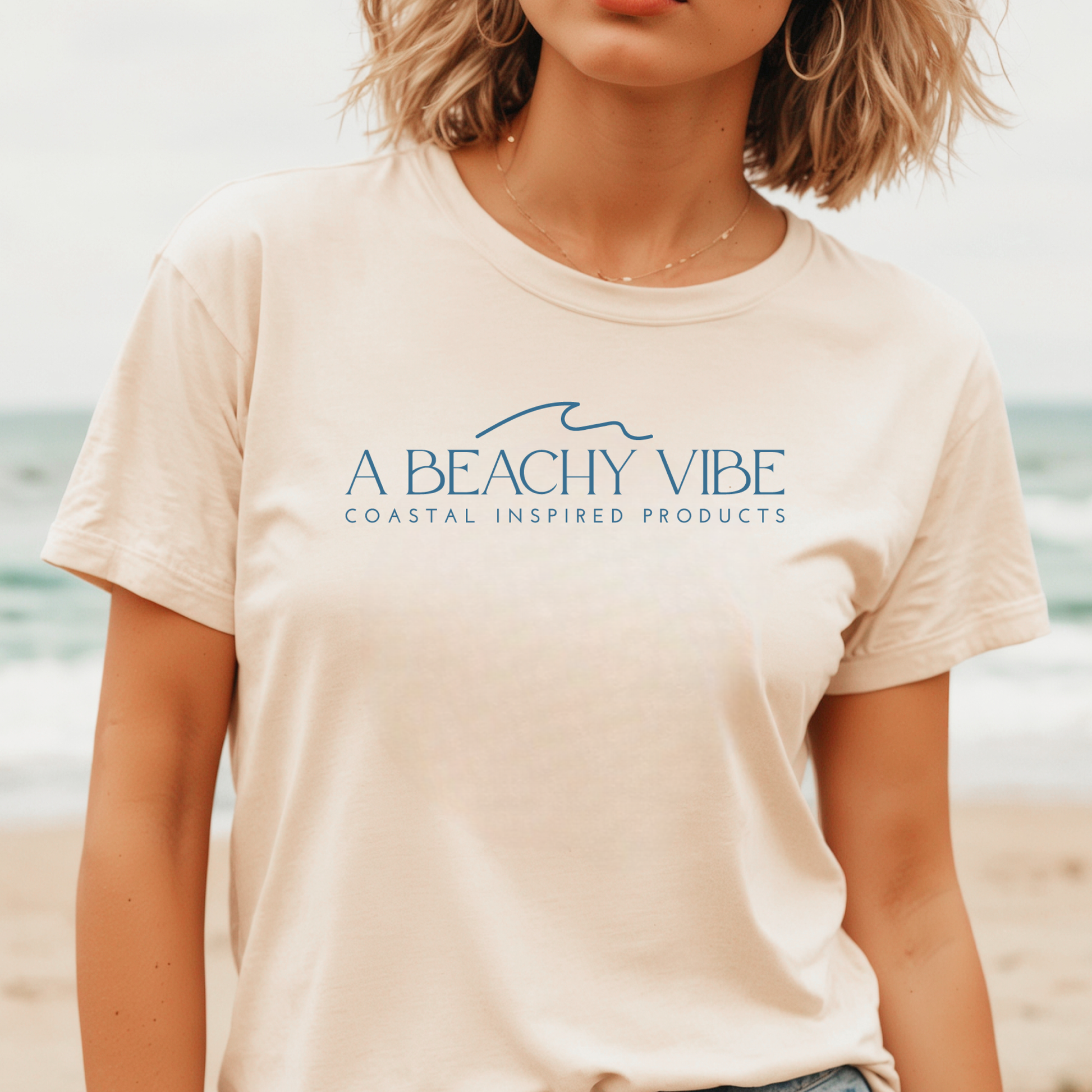 Gildan 5000 "A Beachy Vibe" t shirt with a simple wave graphic in one color. Picture of a girl standing on the beach  wearing a t shirt.