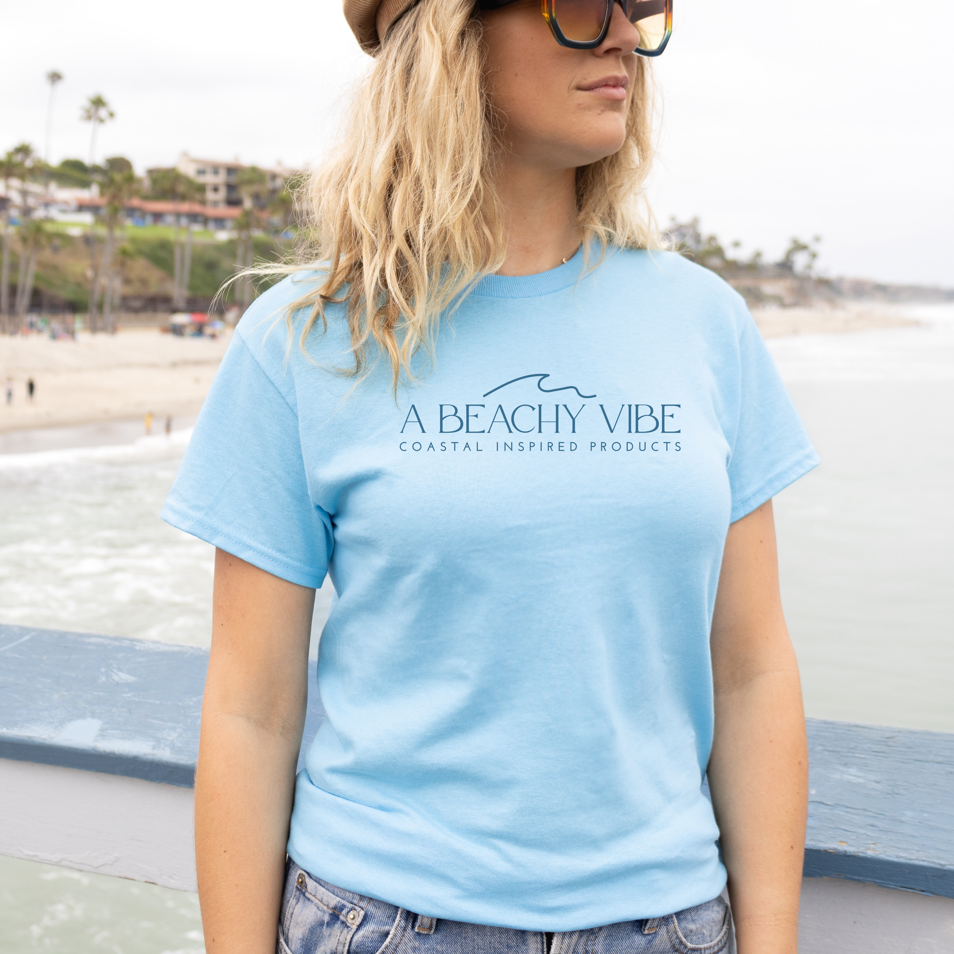 Gildan 5000 "A Beachy Vibe" t shirt with a simple wave graphic in one color. Picture of a girl standing on the beach  wearing a t shirt.