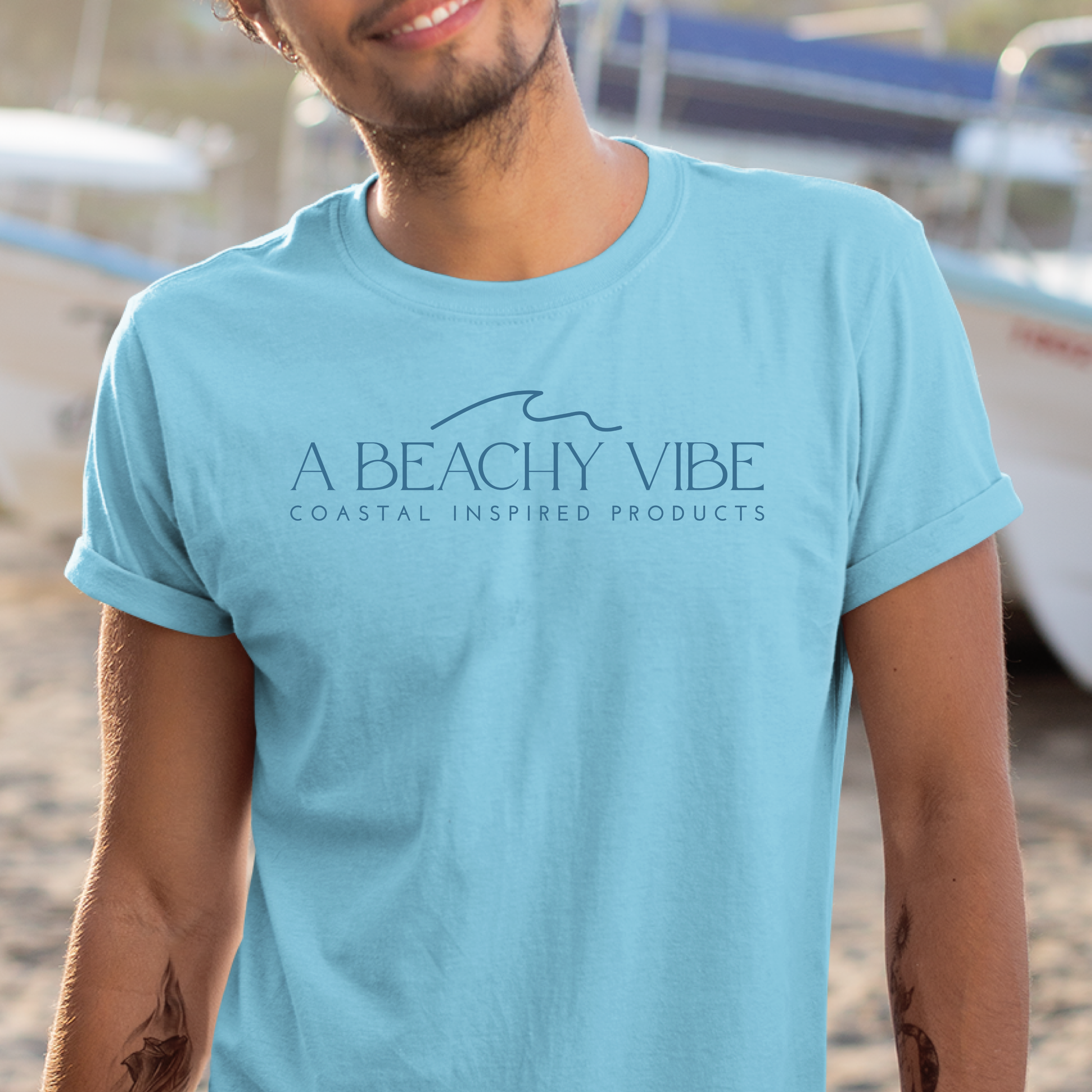 Gildan 5000 "A Beachy Vibe" t shirt with a simple wave graphic in one color. Picture of a man standing next to boat wearing a t shirts.