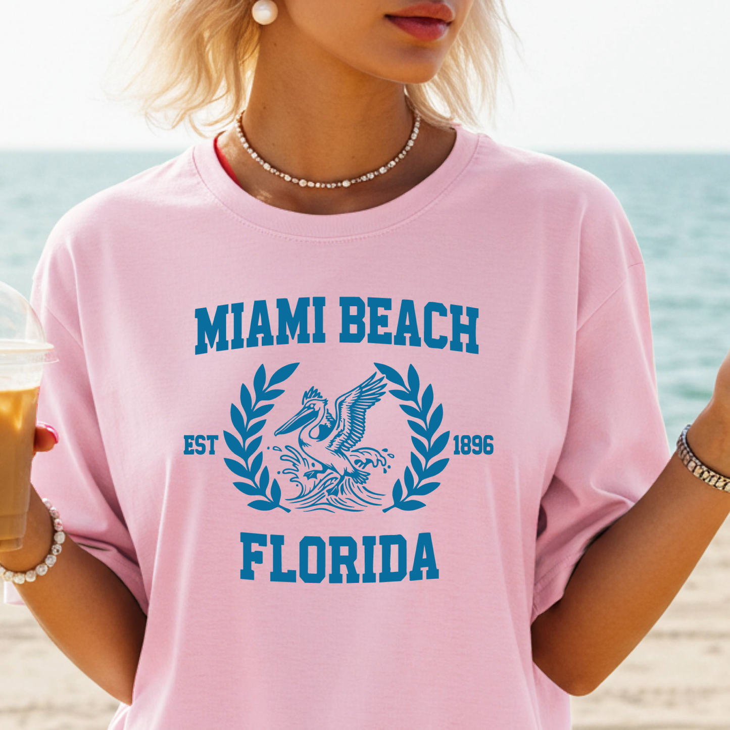 Person wearing a pink 'Miami Beach Florida' t-shirt with a beach background
