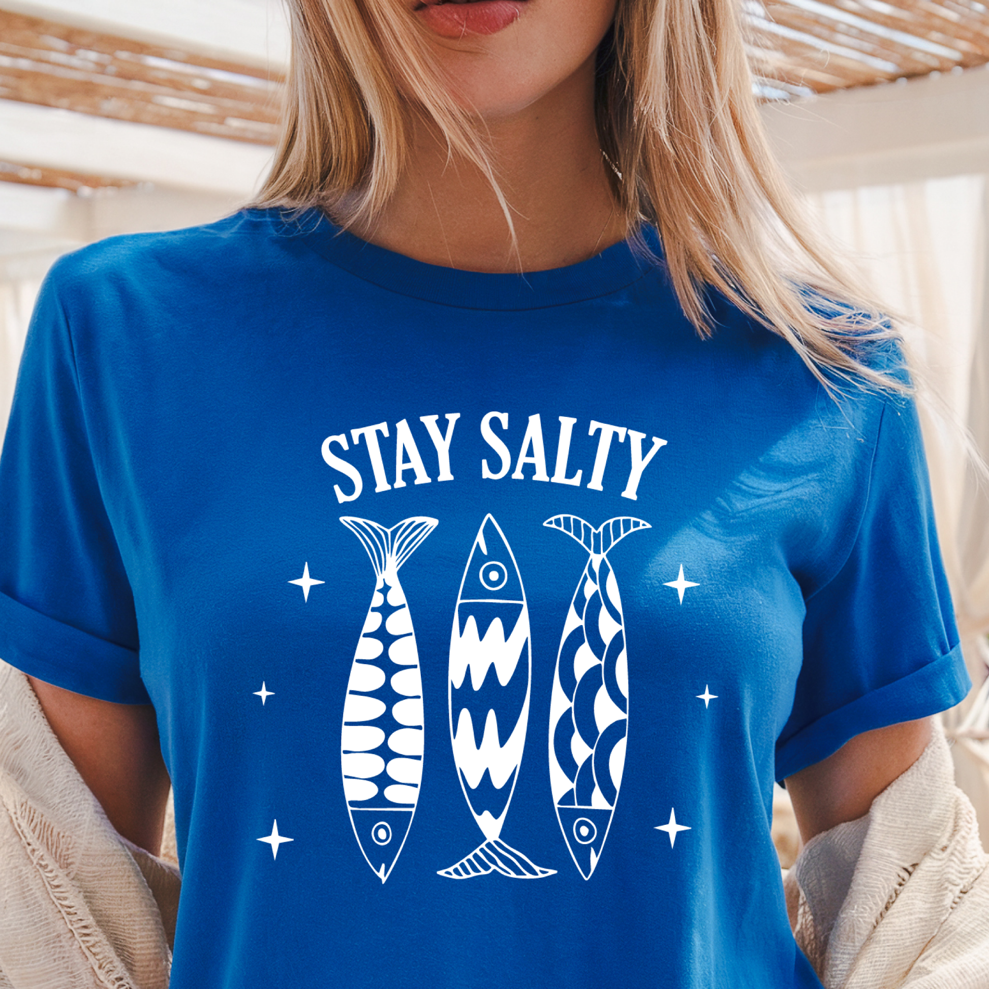 Person wearing a royal blue t-shirt with 'Stay Salty' text and fish graphics.