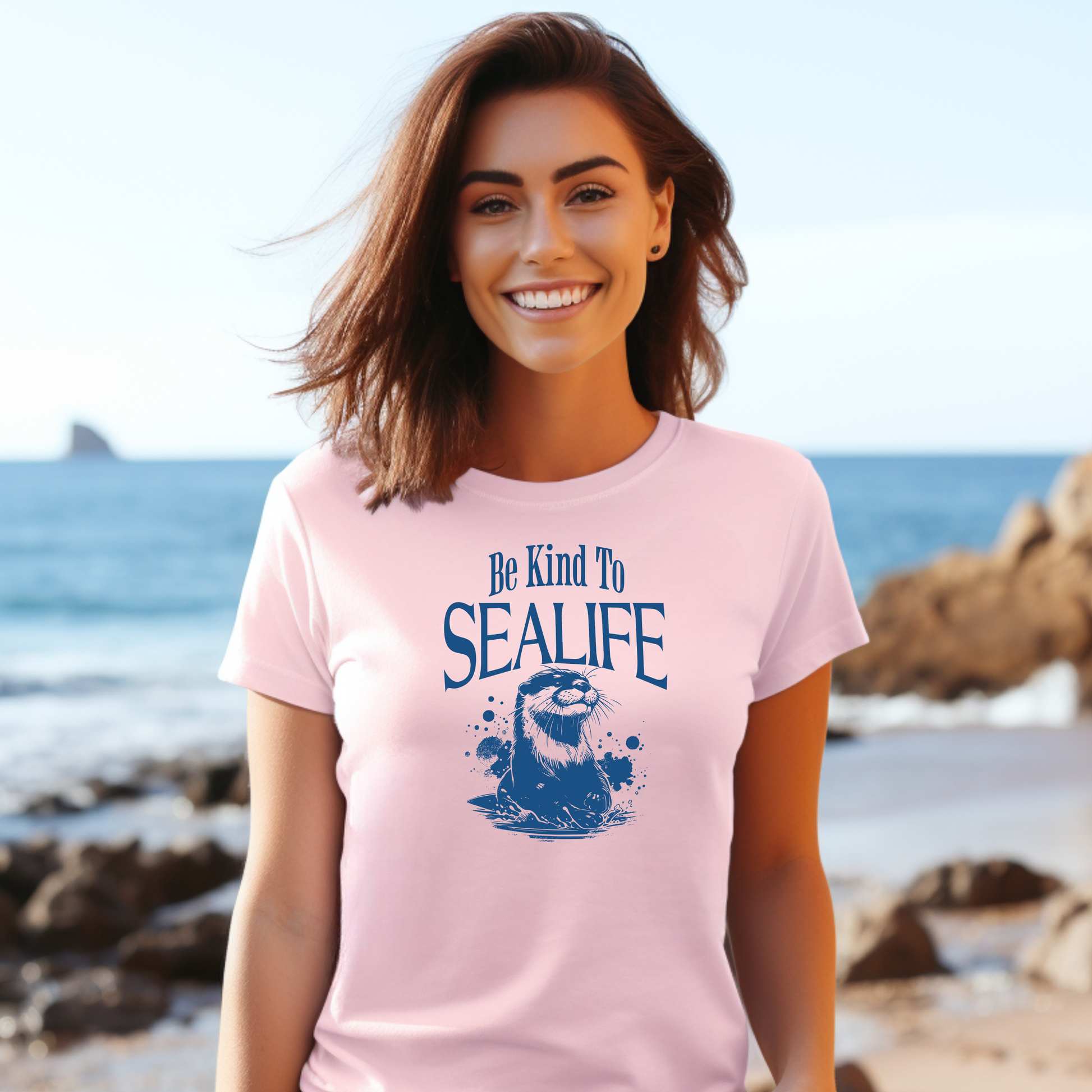 Gildan 5000 "Be Kind To Sealife" t shirt with a otter splashing in the water in a one color graphic. Picture of a girl standing on the beach in a t shirt.