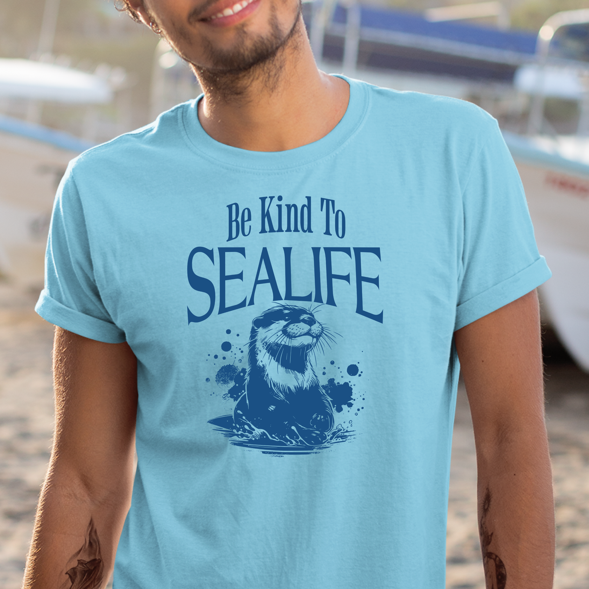 Gildan 5000 "Be Kind To Sealife" t shirt with a otter splashing in the water in a one color graphic. Picture of a man standing by a boat wearing a t shirt,