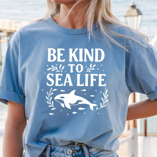 Person wearing a blue t-shirt with 'Be Kind to Sea Life' and an orca whale graphic.