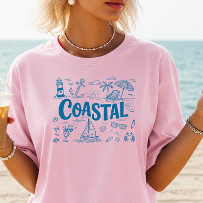 Person wearing a pink t-shirt with 'Coastal' design on a beach