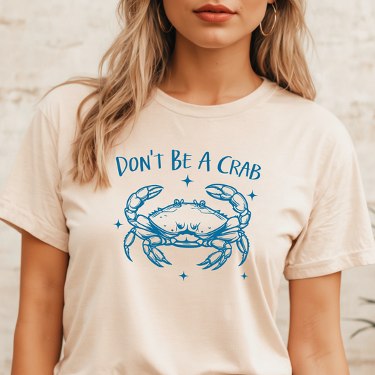 Person wearing a natural colored t-shirt with a blue crab graphic and text 'DON'T BE A CRAB' on a neutral background
