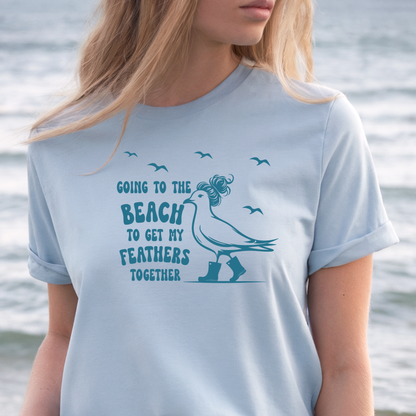 Person wearing a light blue t-shirt with a seagull graphic and text by a body of water.