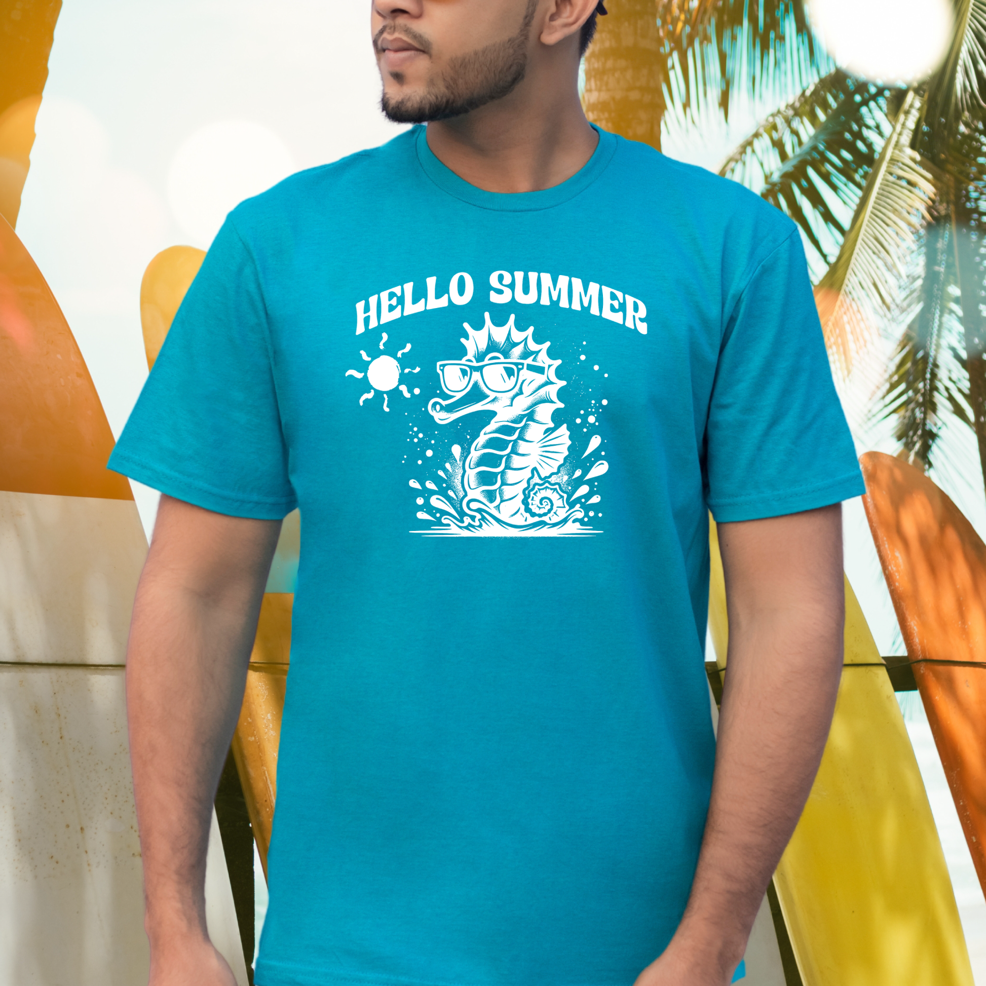 Gildan 5000 "Hello Summer" t shirt with a cute seahorse with sunglasses in one color graphics. Picture of a man standing by surfboards wearing a t shirt.