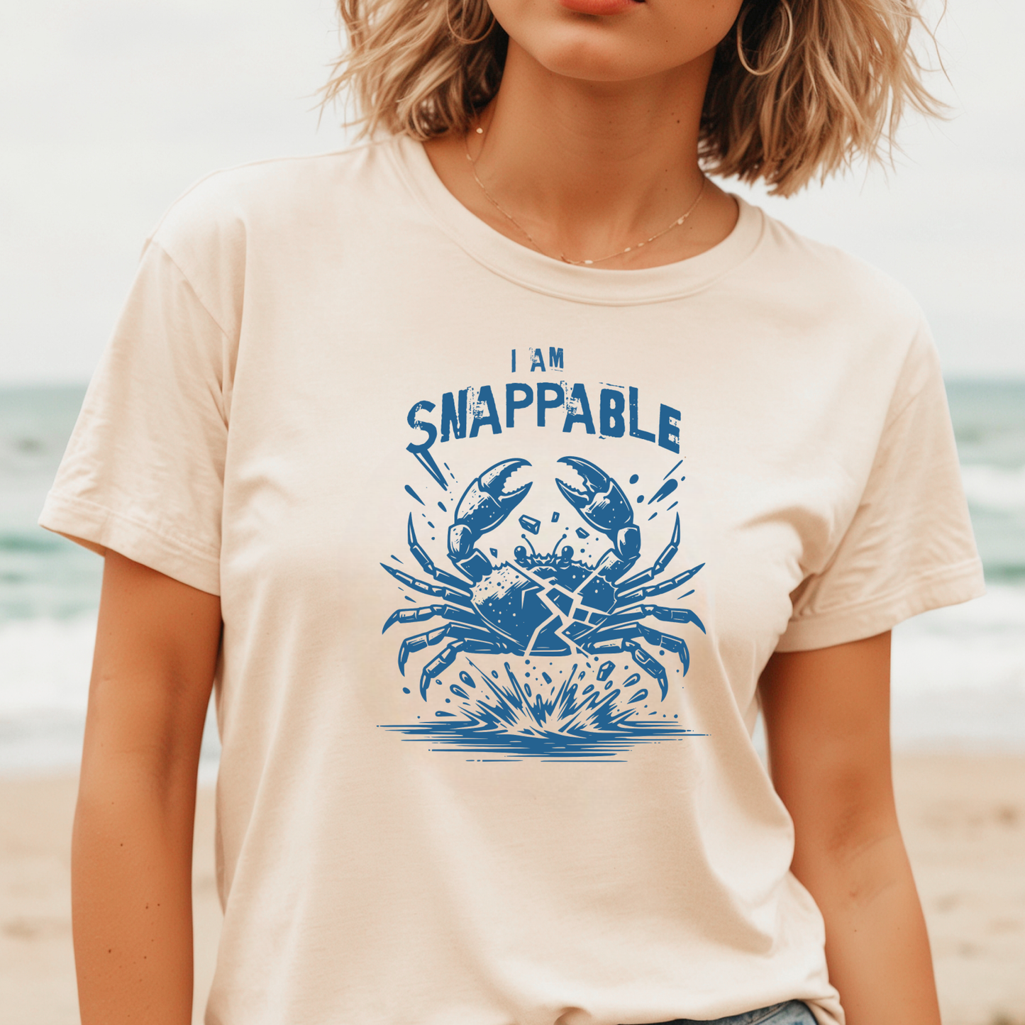 Gildan 5000 "I Am Snappable" t shirt with a crab cracked in half in a one color graphic. Picture of a girl standing on the beach wearing a t shirt.